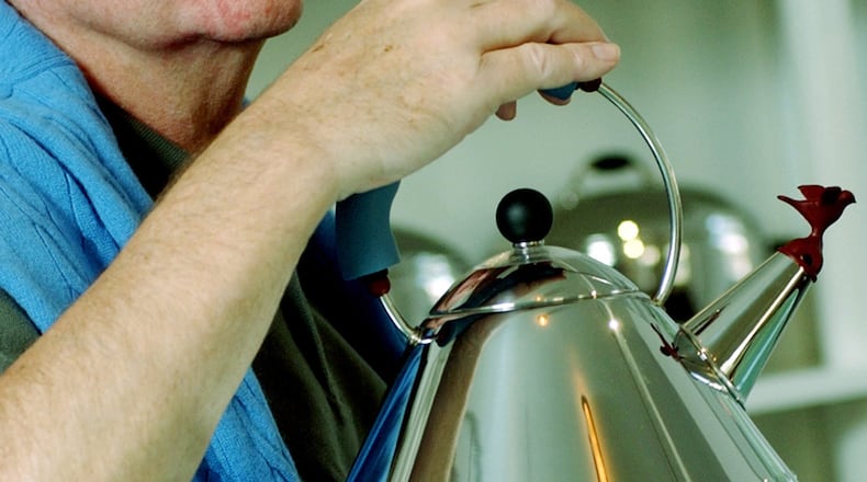 FILE- In this Oct. 21, 2003 file photo, architect and designer Michael Graves poses with a teapot he designed at his studio in Princeton, N.J. Graves, who designed modern and whimsical postmodern structures and later household goods sold at Target stores has died. He was 80 years old. (AP Photo/Daniel Hulshizer, file)