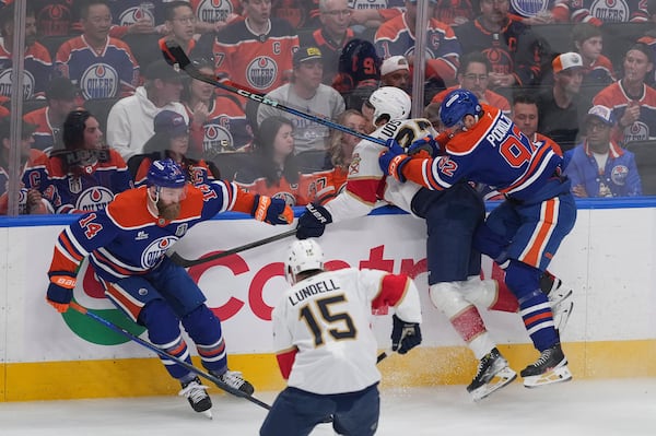 Edmonton Oilers' Vasily Podkolzin (92) checks Florida Panthers' Eetu Luostarinen during the first period in Game 1 of the NHL hockey Stanley Cup final series in Edmonton, Alberta, Wednesday, June 4, 2025. (Darryl Dyck/The Canadian Press via AP)