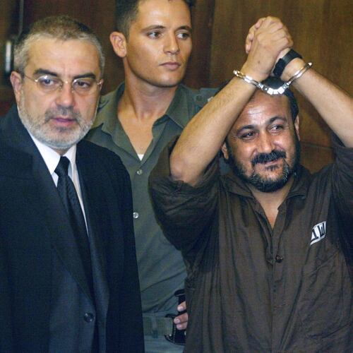 FILE - Marwan Barghouti, center, raises his handcuffed hands in the air on the opening day of his trial in Tel Aviv, Israel, Aug. 14, 2002. (AP Photo/Brennan Linsley, File)