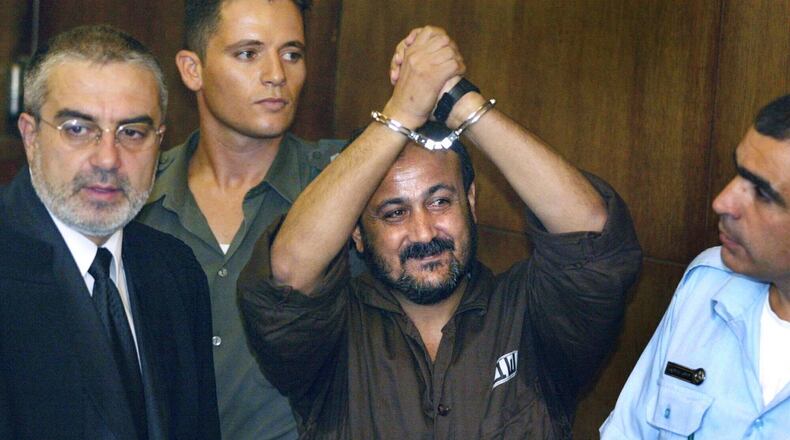 FILE - Marwan Barghouti, center, raises his handcuffed hands in the air on the opening day of his trial in Tel Aviv, Israel, Aug. 14, 2002. (AP Photo/Brennan Linsley, File)