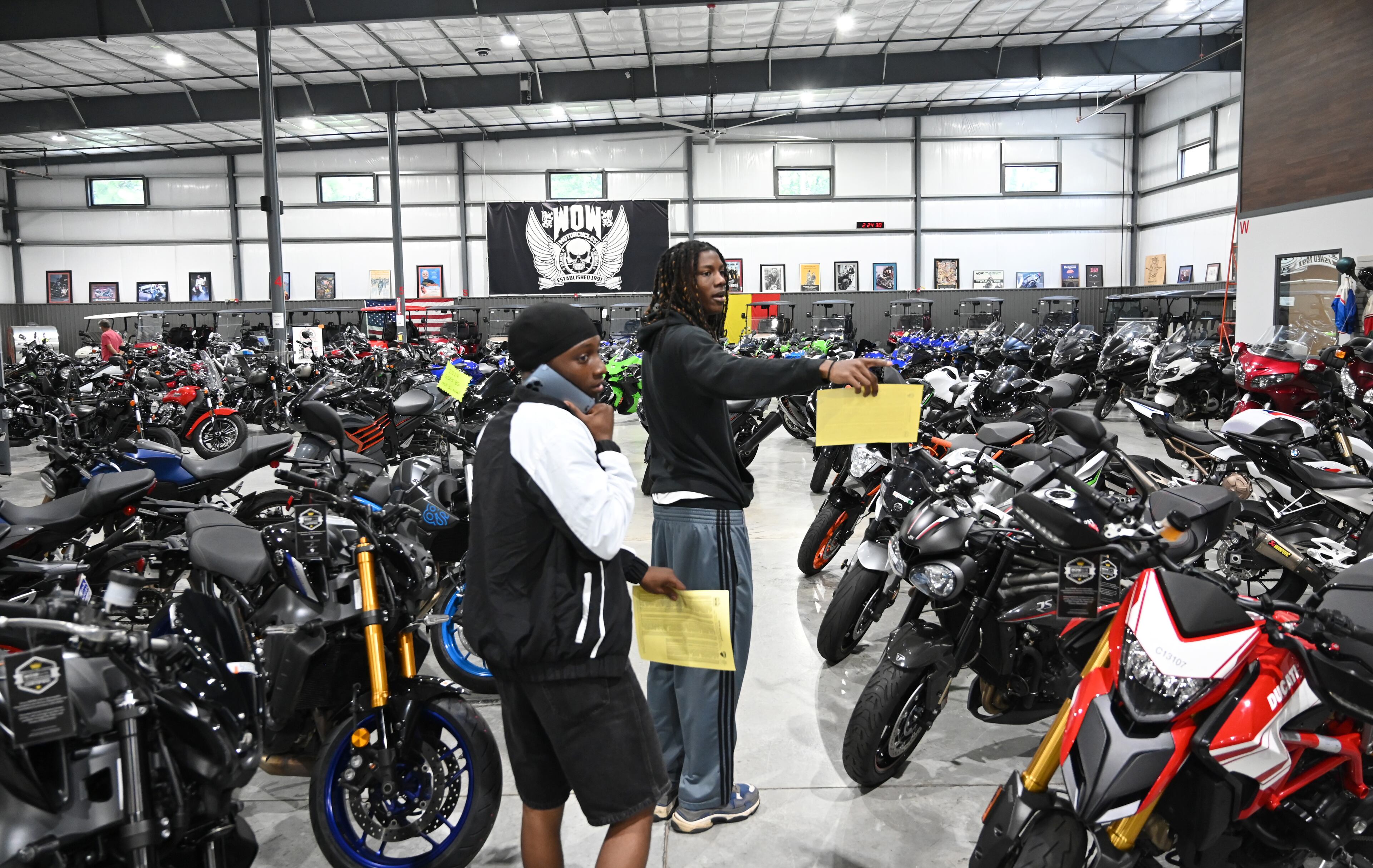 Customers Kim Peterson (left) and Dallas Greene visit WOW Motorcycles on Thursday, July 24, 2025, in Marietta. Motorcycling is a small community, but it allows people from all walks of life to instantly bond, according to Candy Hunter. (Hyosub Shin/AJC)