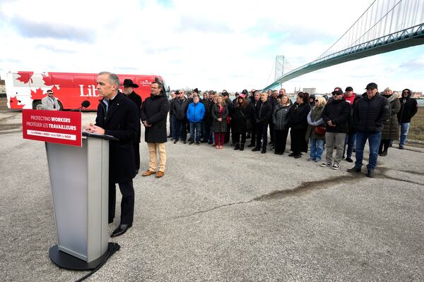 Unifor auto workers stand behind Liberal Leader Mark Carney as he speaks during a campaign stop at the Ambassador Bridge in Windsor, Ont., on Wednesday, March 26, 2025. (Frank Gunn /The Canadian Press via AP)