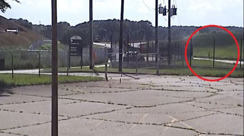 A screen shot of surveillance video showing a man jumping a fence at the Atlanta airport