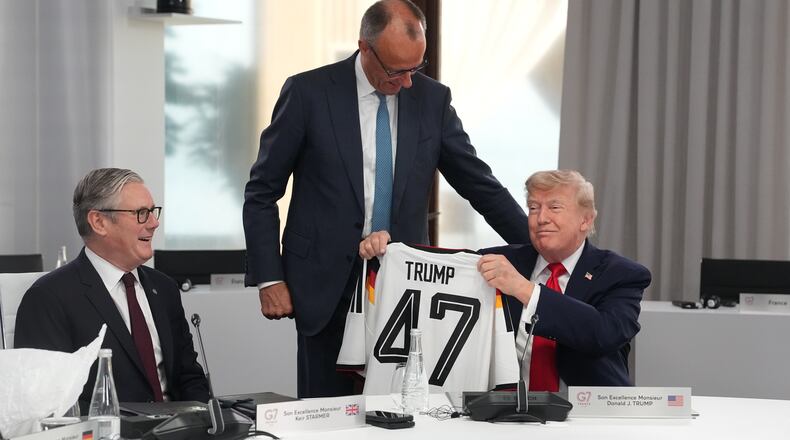 U.S. President Donald Trump, right, holds up a jersey with the number 47 on it as British Prime Minister Keir Starmer, left, and German Chancellor Friedrich Merz look on during a working session at the G7 summit in Evian-les-Bains, France, Tuesday, June 16, 2026. (AP Photo/Thibault Camus, Pool)