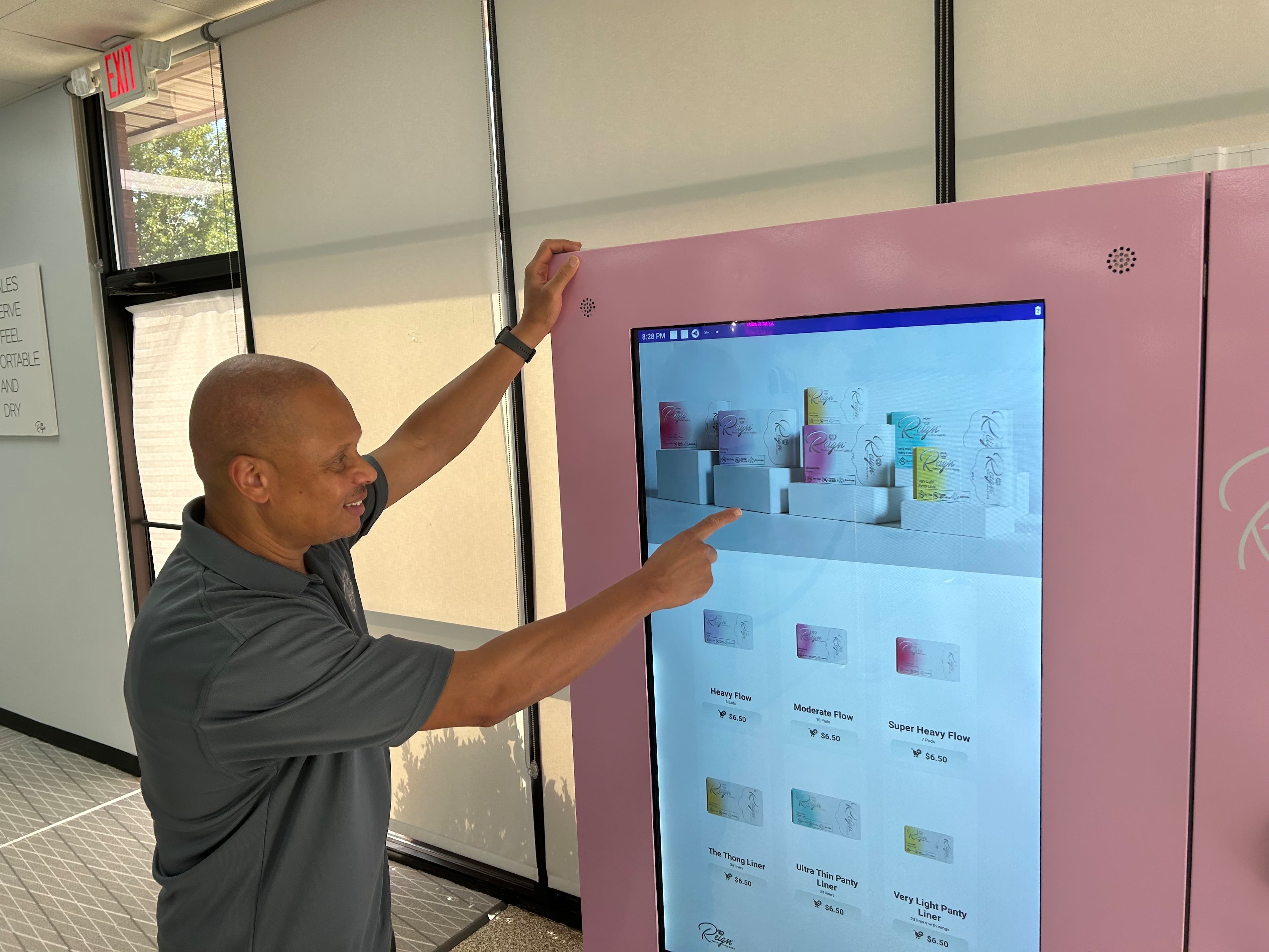Demond Crump Sr. shows off a prototype for a Reign sanitary napkin vending machine that could be placed at airports and on college campuses. (Thomas Lake/AJC)