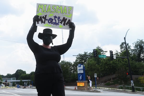 A protester walks across the street outside of the CDC dressed as a "preventable disease" in Atlanta on Wednesday, June 25, 2025. (Abbey Cutrer/AJC)