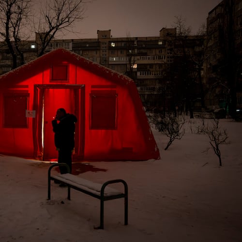 A man smokes outside of an emergency tent where people can warm up following Russia's regular air attacks against the country's energy objects, that leave residents without power, water and heating in the dead of winter, in Kyiv, Ukraine, Tuesday, Jan. 13, 2026. (AP Photo/Danyil Bashakov)
