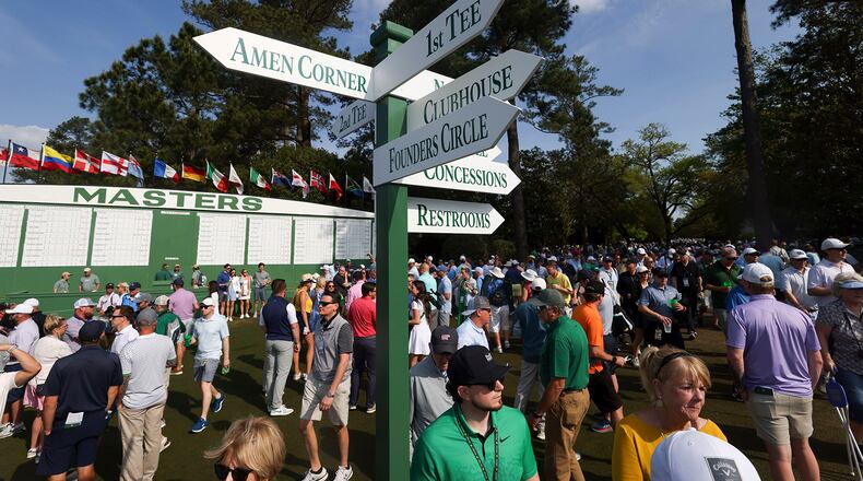 Patrons walk around a sign posting directions to famous areas of interest such as; Amen Corner, with the Masters scoreboard in the background near the first fairway during the practice round of the 2024 Masters Tournament at Augusta National Golf Club, Wednesday, April 10, 2024, in Augusta, Georgia. (Jason Getz/The Atlanta Journal-Constitution/TNS)