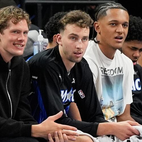 **HOLD FOR STORY BY ROB MADDIE**Orlando Magic players and brothers Moritz Wagner, left, and Franz Wagner, center, watch the first half of an NBA basketball game with teammate Paolo Banchero against the Golden State Warriors, Tuesday, Nov. 18, 2025, in Orlando, Fla. (AP Photo/John Raoux)