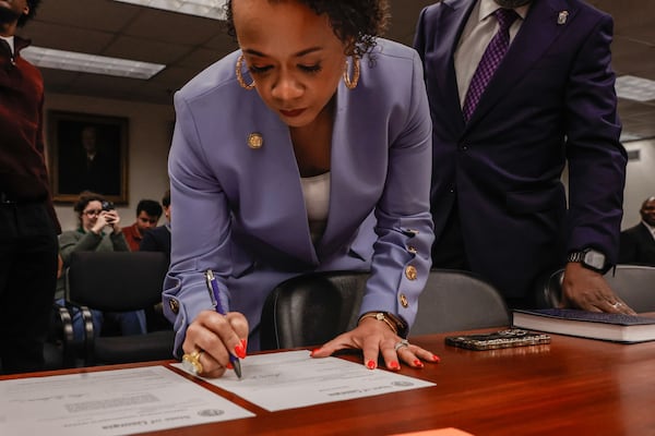 Georgia Public Service Commissioner-elect Alicia Johnson (center) signs the loyalty oath after being sworn in at PSC headquarters in Atlanta on Monday, Dec. 29, 2025. (Natrice Miller/AJC)