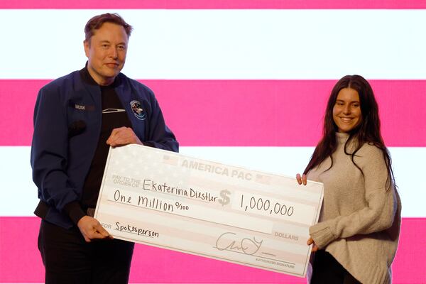 Elon Musk presents a check for $1 million dollars during a town hall Sunday, March 30, 2025, in Green Bay, Wis. (AP Photo/Jeffrey Phelps)