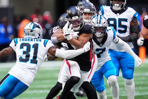 Atlanta Falcons running back Bijan Robinson (7) carries between Carolina Panthers cornerback Corey Thornton (31) and safety Tre'von Moehrig (7) in the first half of an NFL football game, Sunday, Nov. 16, 2025, in Atlanta. (Mike Stewart/AP)