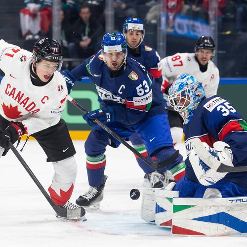 Canada's Macklin Celebrini, left, vies for the puck against Italy's Alex Trivellato, center, and Italy's goaltender Davide Fadani, right, during the 2026 IIHF Men's Ice Hockey World Championship preliminary round group B game between Italy and Canada, in Fribourg, Switzerland, Saturday, May 16, 2026. (Cyril Zingaro/Keystone via AP)