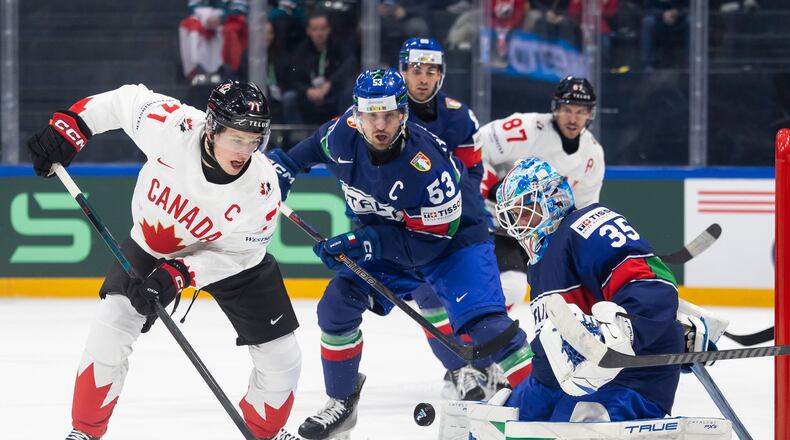 Canada's Macklin Celebrini, left, vies for the puck against Italy's Alex Trivellato, center, and Italy's goaltender Davide Fadani, right, during the 2026 IIHF Men's Ice Hockey World Championship preliminary round group B game between Italy and Canada, in Fribourg, Switzerland, Saturday, May 16, 2026. (Cyril Zingaro/Keystone via AP)