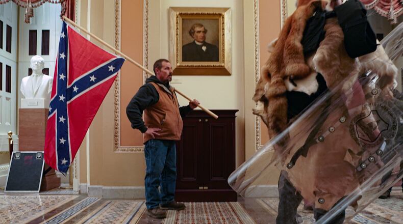 A supporter of President Donald Trump carries a Confederate battle flag inside the Capitol building in Washington, as a mob of his supporters protest the presidential election results, on Wednesday, Jan. 6, 2021. Historians said it was unnerving to see a man carry the flag inside the Capitol, something not even Confederate soldiers were able to do during the Civil War. (Erin Schaff/The New York Times)