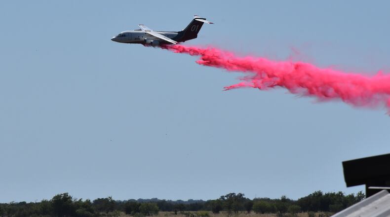 A tanker aircraft dumps fire retardant on a field southwest of Salado, Texas, Wednesday, Aug. 12, 2026, after a military helicopter crashed and sparked a grass fire. (Brent Johnson/The Killeen Daily Herald via AP)