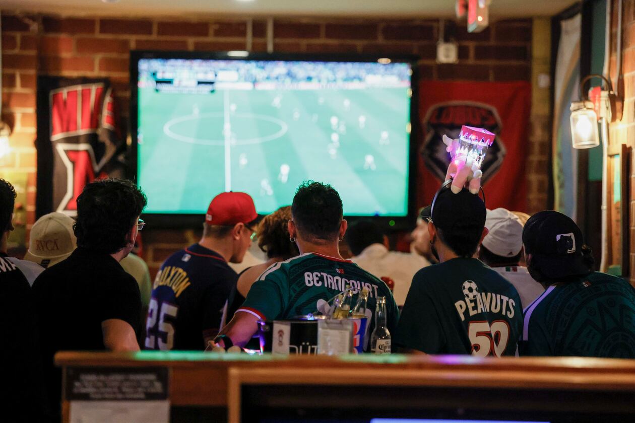 A group of customers, some wearing Mexico jerseys, watch a World Cup game on screens at Woofs Sport Bar in Midtown on Sunday, July 5, 2026. Woofs is the official location for Pride House ATL, the city’s designated hub for LGBTQ+ soccer fans during the FIFA World Cup. (Miguel Martinez/AJC)