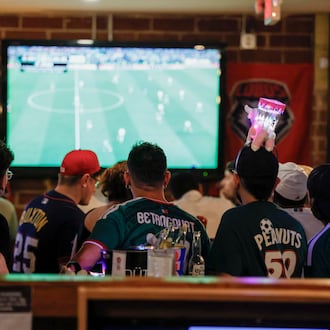 A group of customers, some wearing Mexico jerseys, watch a World Cup game on screens at Woofs Sport Bar in Midtown on Sunday, July 5, 2026. Woofs is the official location for Pride House ATL, the city’s designated hub for LGBTQ+ soccer fans during the FIFA World Cup. (Miguel Martinez/AJC)