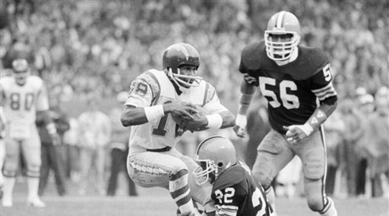 San Diego Chargers receiver Charlie Joiner (18) is dragged down by Cleveland Browns defender Clarence Scott after a catch in the first quarter of the game in Cleveland Stadium, Dec. 5, 1982. Coming up from behind is Browns' linebacker Chip Banks (56). (AP Photo/Bruce Zake)