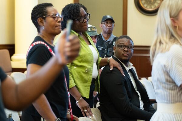 Riverdale City Council member Josie Singletary, who said she is a big supporter of Stockbridge Mayor Jayden Williams, keeps her hand on his shoulder as they listen to City Attorney Quinton Washington speak to journalists Saturday, Aug. 22, 2026. (Ben Gray for the AJC)