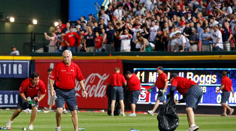 Braves ground crew members scramble to pick up debris as fans toss it onto the field after the umpires made a controversial infield fly call during the eighth inning in the National League wild card game at Turner Field in Atlanta on Friday , Oct. 5, 2012.