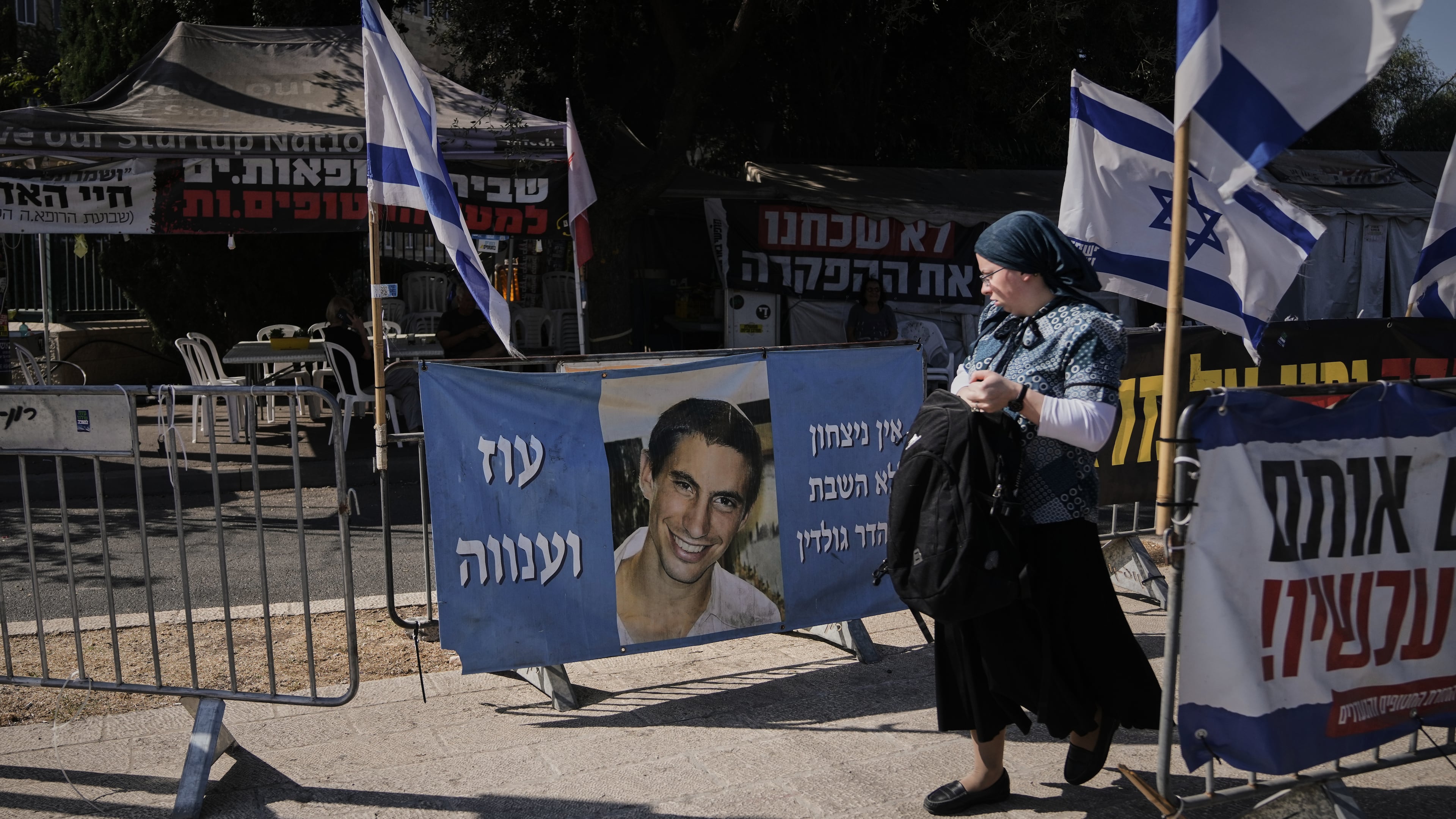 A woman walks past a photo of Hadar Goldin, an Israeli soldier killed in 2014 whose body has been held in Gaza since then, in Jerusalem, Sunday, Nov. 9, 2025. (AP Photo/Mahmoud Illean)