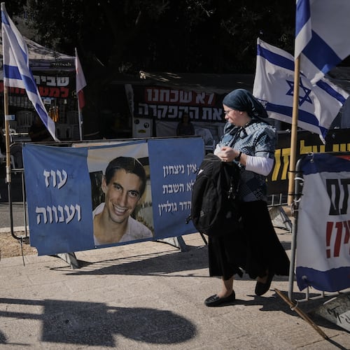 A woman walks past a photo of Hadar Goldin, an Israeli soldier killed in 2014 whose body has been held in Gaza since then, in Jerusalem, Sunday, Nov. 9, 2025. (AP Photo/Mahmoud Illean)