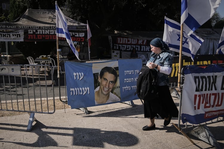 A woman walks past a photo of Hadar Goldin, an Israeli soldier killed in 2014 whose body has been held in Gaza since then, in Jerusalem, Sunday, Nov. 9, 2025. (AP Photo/Mahmoud Illean)