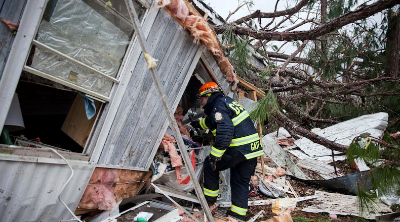 A rescue worker enters a hole in the back of a mobile home Monday, Jan. 23, 2017, in Big Pine Estates that was damaged by a tornado, in Albany, Ga. Fire and rescue crews were searching through the debris, looking for people who might have become trapped when the deadly storm came through. (AP Photo/Branden Camp)