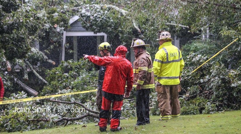 Outside of where a tree crashed into a home and killed a Sandy Springs man, authorities discuss how to get inside the home on Monday, Sept. 11, 2017. (JOHN SPINK/AJC)