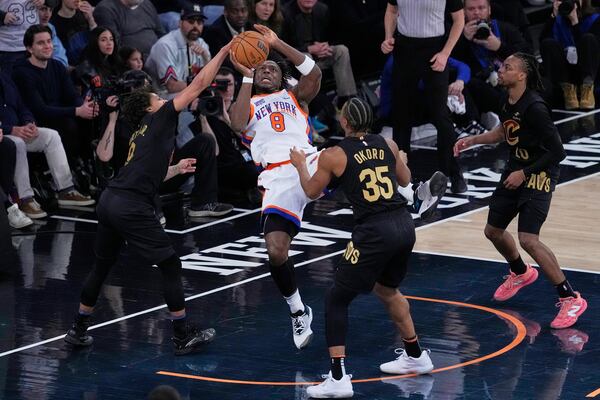 New York Knicks' OG Anunoby, center, looks to pass around Cleveland Cavaliers defender during the first half of an NBA basketball game Friday, April 11, 2025, in New York. (AP Photo/Seth Wenig)