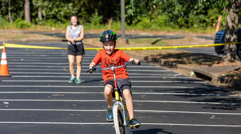 Special needs camper, Banks, takes a victory lap after learning how to ride a two-wheel bike without adaptations during the iCan Bike Alpharetta camp at The Cooler in Alpharetta. PHIL SKINNER FOR THE ATLANTA JOURNAL-CONSTITUTION.