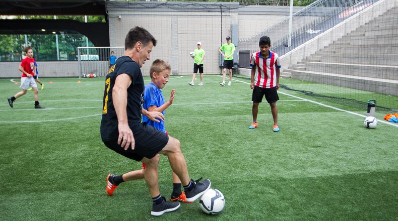 Phil Hill, executive director of Soccer in the Streets, mixes it up with kids at a summer camp at the Five Points MARTA Station. DAVE WILLIAMSON