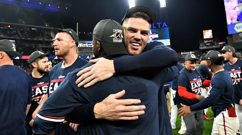 Braves first baseman Freddie Freeman hugs a teammate as the team celebrates on the field after clinching its fourth straight division title with 5-3 victory over the Philadelphia Phillies Thursday, Sept. 30, 2021, at Truist Park in Atlanta. (Hyosub Shin/hshin@ajc.com)