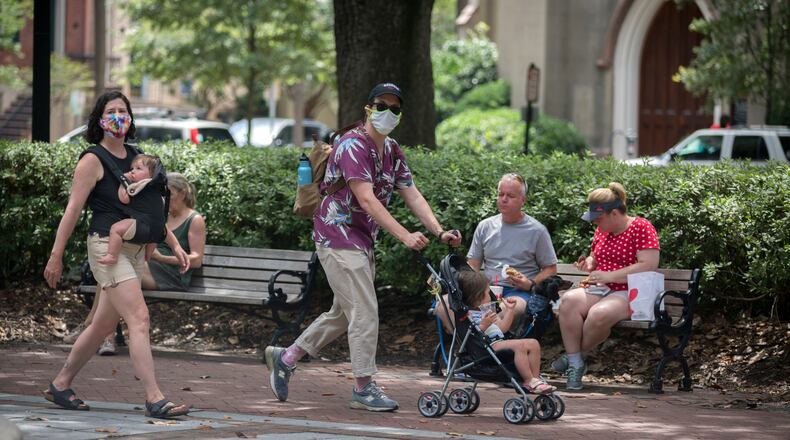 SAVANNAH, GA - June 30, 2020: A family wearing masks walk through one of Savannah's historic squares while other visitors eat on a bench near by. Savannah on Tuesday became the first major city in Georgia to require the use of face masks, setting up a potential showdown with Gov. Brian Kemp over whether local officials can take more sweeping steps than the state to contain the coronavirus. (AJC Photo/Stephen B. Morton)