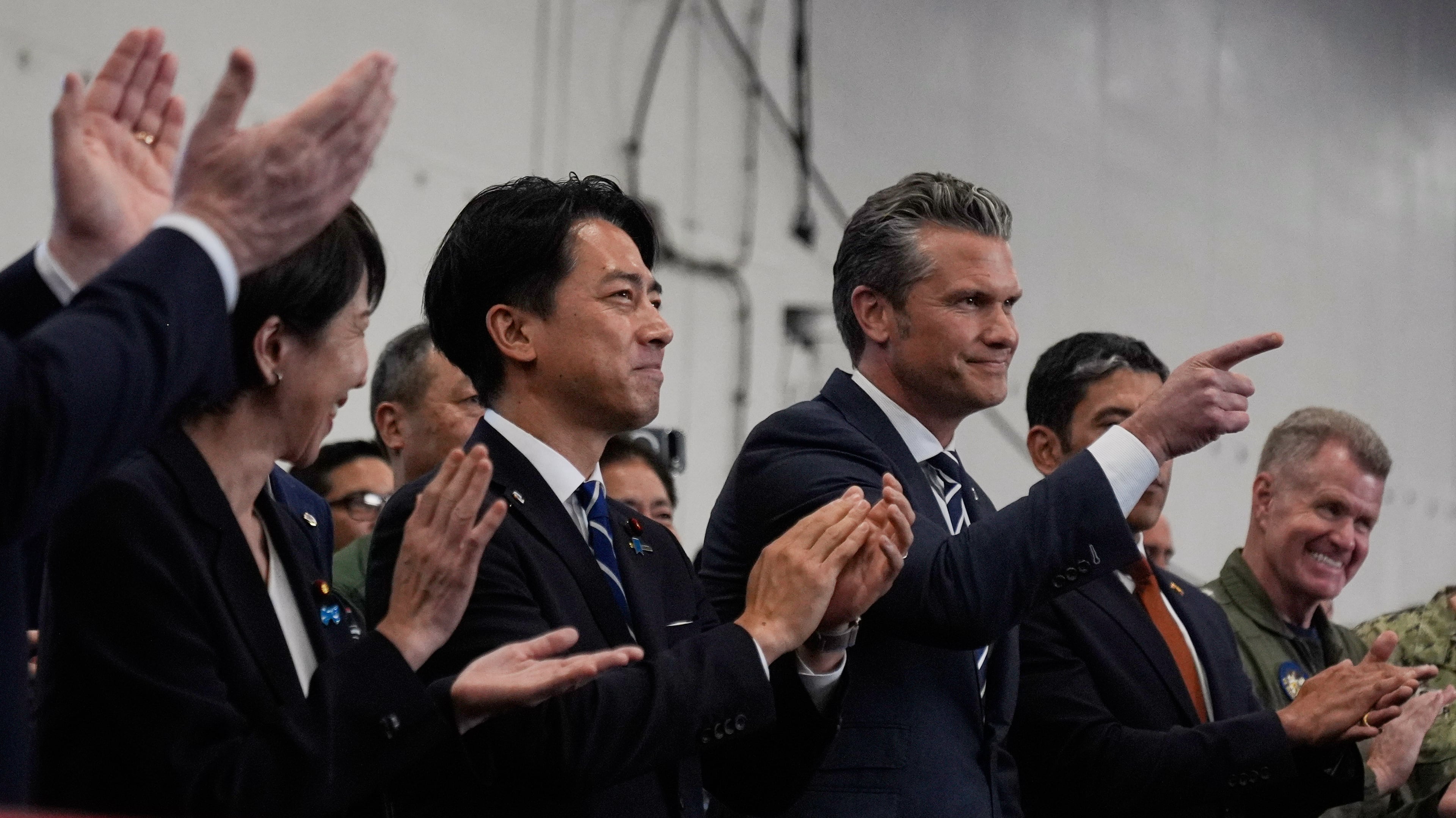U.S. Defense Secretary Pete Hegseth, center right, with Japanese Prime Minister Sanae Takaichi, left, and Defense Minister Shinjiro Koizumi, gestures as they listen to President Donald Trump speak to members of the military aboard the USS George Washington, an aircraft carrier docked at an American naval base, in Yokosuka, south of Tokyo, Tuesday, Oct. 28, 2025. (AP Photo/Mark Schiefelbein)