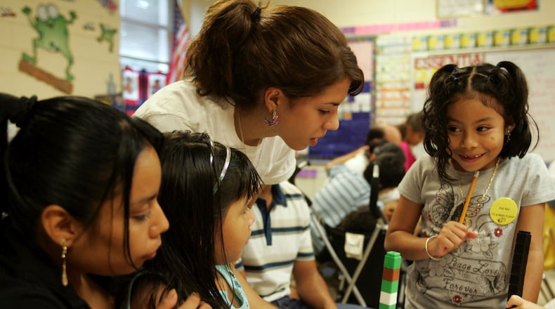 SANDY SPRINGS - A mother and daughter listen to Maria Guerra translate an assignment for her other daughter during a parents meeting at High Point Elementary School in Sandy Springs. More than two dozen Spanish-speaking student interpreters from Riverwood High School help translate for non-English-speaking parents at Fulton County Schools events like PTA meetings, parent-teacher conferences and other activities. AJC file photo.
