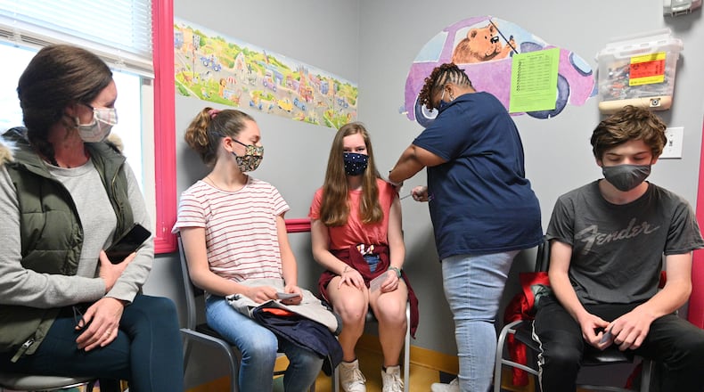 Margarett Bell, 14, receives a first dose of the Pfizer-BioNTech vaccine from Melissa Dalton, RMA, as her mother Jessica Bell (left), sister Mary Frances Bell, 12, and brother Griffin Bell (right), 17, look at Dekalb Pediatric Center on May 12, 2021.