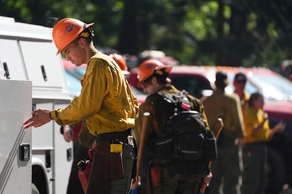A firefighter with the United States Forest Service prepares gear at a staging area near the scene the day after a shooter ambushed and killed multiple firefighters responding to a wildfire at Canfield Mountain Monday, June 30, 2025, in Coeur D'Alene, Idaho. (AP Photo/Lindsey Wasson)