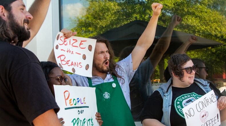 Starbucks employees, union workers and former Starbucks employees, including Camden Mitchell, from left, Courtney Cook, Walker Stipe and Page Smith, picket at the Howell Mill location while on strike Sunday, July 17, 2022 after voting to join the union and asking for guaranteed work hours, benefits and a contract to protect the hourly workers.  Starbucks management has not responded to requests to start negotiation.  (Jenni Girtman for The Atlanta Journal-Constitution)