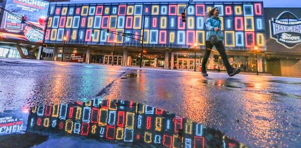 File photo: Jennifer Toland from Boise, Idaho crosses Marietta Street in front of the colorful facade of the College Football Hall of Fame in downtown Atlanta earlier this year. JOHN SPINK/JSPINK@AJC.COM
