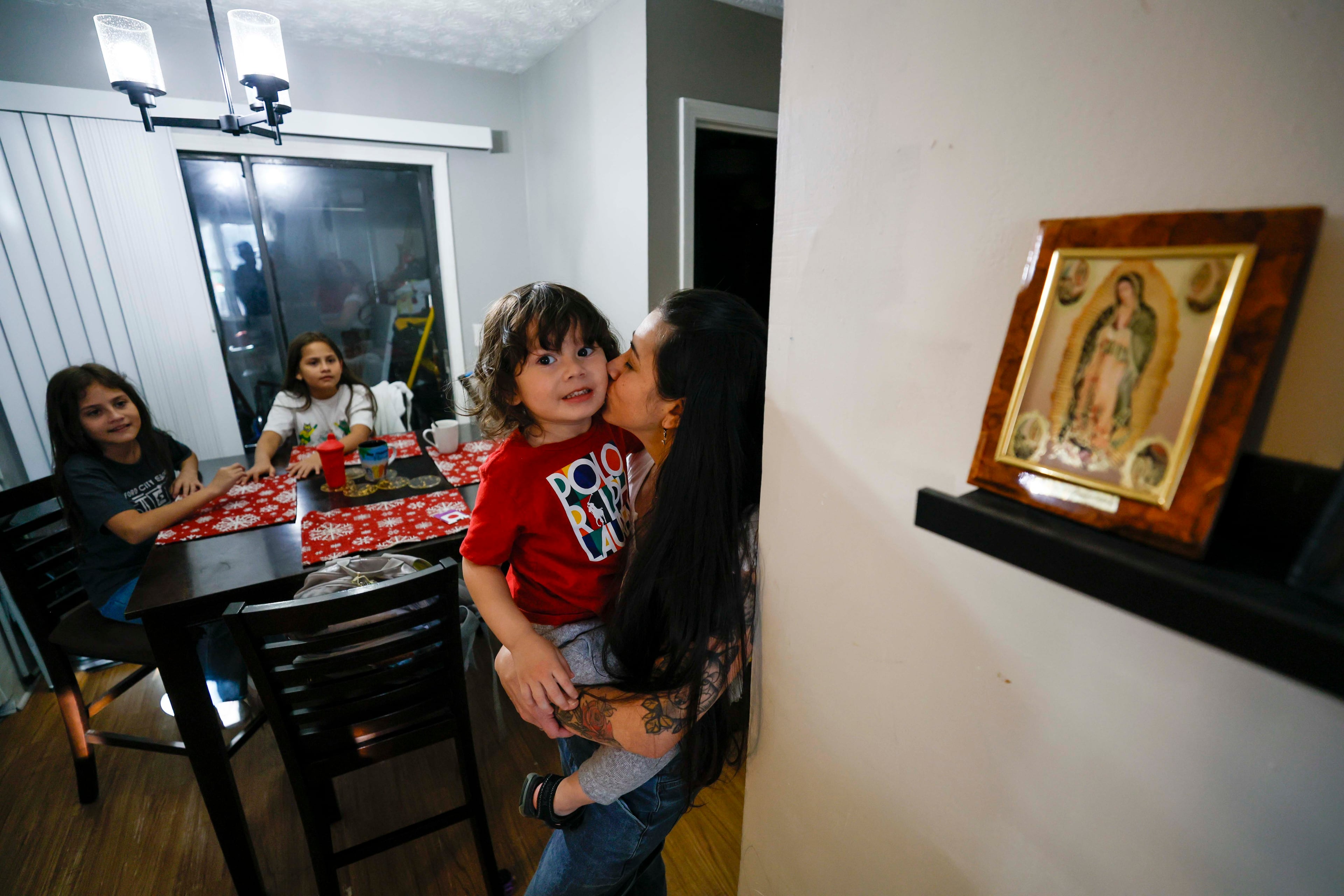 Ceudy Gutierrez kisses her 2-year-old son, Matias, with her two daughters, Maria Jose and Maria Camila, in the background at their home in Buford, GA, on Tuesday, Nov. 18, 2025. (Miguel Martinez/AJC)