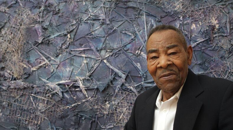 The late Thornton Dial poses with his monumental painting, “Crossing Waters,” during the 2012 opening of “Hard Truths,” a major retrospective staged at the High Museum of Art surveying 20 years of the artists’s work. PHIL SKINNER /