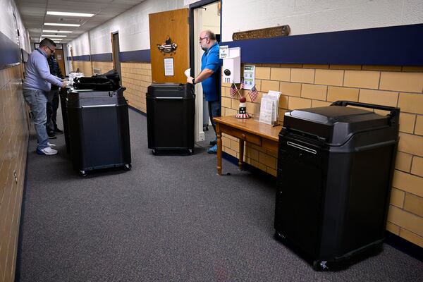 Christopher Prue, president of the Registrars of Voters Association of Connecticut, right, moves new voting tabulators out of his office at the Registrars of Voters to be redistributed to other towns, Thursday, March 27, 2025, in Vernon, Conn. (AP Photo/Jessica Hill)