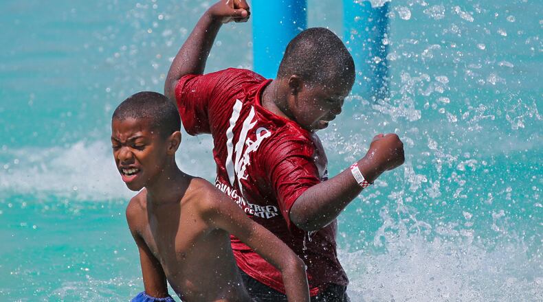 Malik Ambles, left, 11, and Jesse Sands, 12, right, feel the coolness of the water spray at Clayton County International Park in summer 2012. JOHN SPINK / JSPINK@AJC.COM