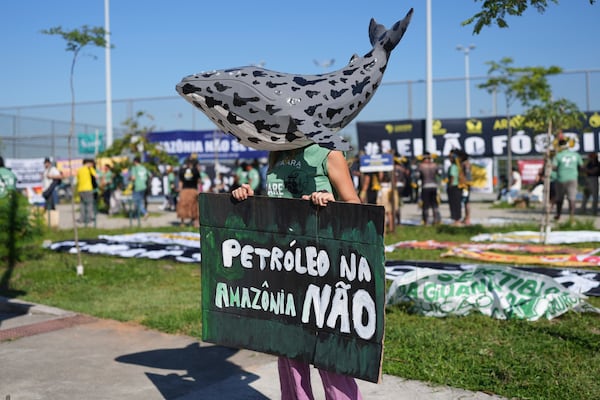 An protester wearing a whale mask holds a sign that reads in Portuguese, "No oil in the Amazon" to demonstrate against the auction of dozens of oil blocks, including blocks near the mouth of the Amazon River, in Rio de Janeiro, Tuesday, June 17, 2025. (AP Photo/Silvia Izquierdo