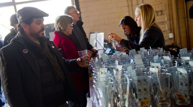 Scott Hutchison (left) grabs his glass and tasting tickets as he enters the Great Southern Craft Beer Competition Kickoff Party at Monday Night Brewing in Atlanta. JONATHAN PHILLIPS / SPECIAL