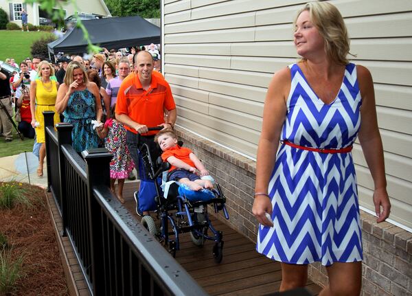 Bill and Stacy Halstead wheel their son Tripp up the custom ramp to get a first look at the makeover by Sunshine on a Ranney Day done to their Jefferson home in 2013. PHIL SKINNER / AJC File