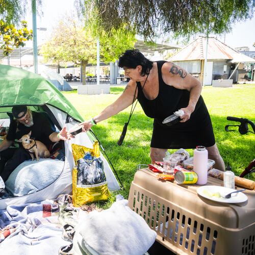 Jan De Jonge and fiancé Sher Stuckman set up a tent with their belonging and pet outside the Elks Lodge in Garden Grove, Calif., on Monday, May 25, 2026. (AP Photo/Ethan Swope)