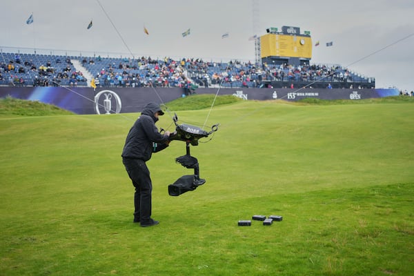 A technician changes the camera batteries on spidercam on the 18th green during the first round of the British Open golf championship at the Royal Portrush Golf Club, Northern Ireland, Thursday, July 17, 2025. (AP Photo/Jon Super)